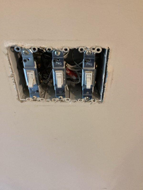 Responded to non-functioning exterior porch light controlled by interior living room switch. Verified breaker was operational and removed wall plate to access triple switch assembly. Diagnosed faulty switch in the three-gang box, identified correct wiring connections (black, white, and red conductors), and replaced defective switch. Tested operation and confirmed exterior light now functions properly when toggled from interior switch location.