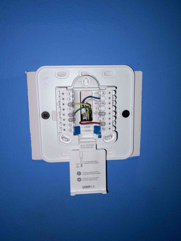 Completed HVAC thermostat installation with full system wiring configuration. Mounted new programmable digital thermostat unit (UWP16 model) on wall, connected multi-stage heating and cooling wires to proper terminal blocks including common, heating, cooling, and accessory circuits, verified secure connections and proper labeling, and confirmed unit powered on successfully. All wiring meets code requirements and manufacturer specifications for optimal system operation.