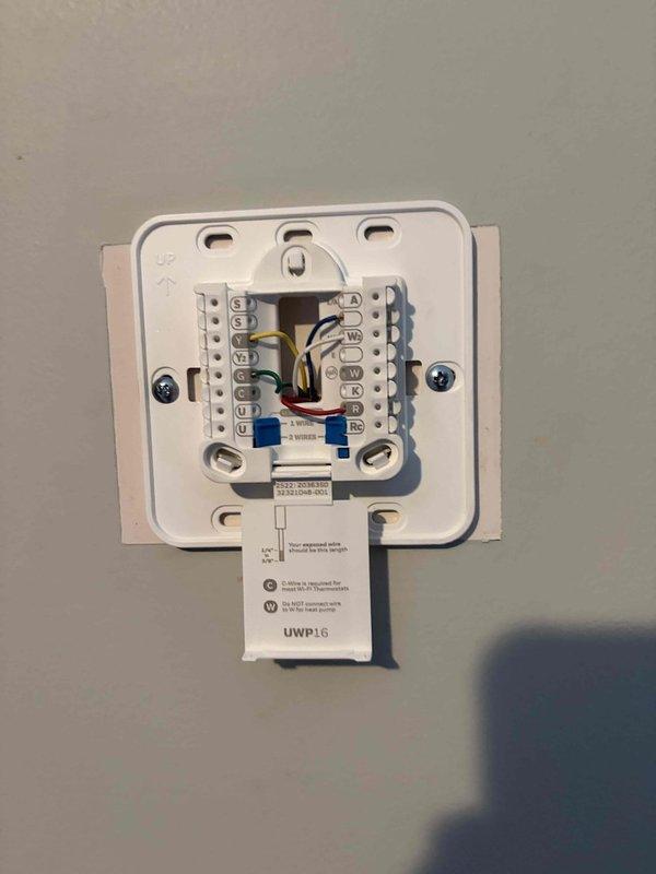 Completed HVAC thermostat installation with full system wiring configuration. Mounted new programmable digital thermostat unit (UWP16 model) on wall, connected multi-stage heating and cooling wires to proper terminal blocks including common, heating, cooling, and accessory circuits, verified secure connections and proper labeling, and confirmed unit powered on successfully. All wiring meets code requirements and manufacturer specifications for optimal system operation.