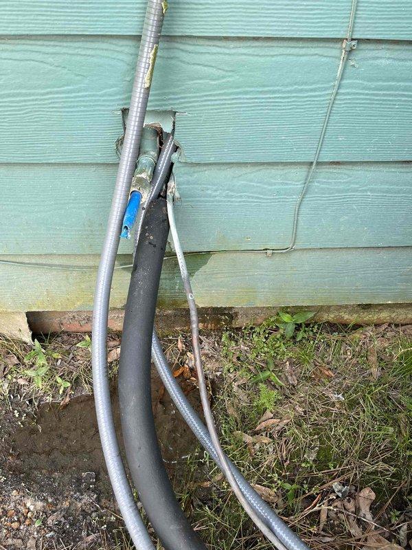 Responded to service call regarding low voltage whip requiring replacement at exterior HVAC unit location. Upon arrival, inspected electrical conduits and low voltage wiring running along building foundation to outdoor condensing unit. Found deteriorated low voltage whip with visible corrosion at connection point and compromised wire insulation exposed to weather elements. Documented existing conditions showing weathered metal junction connections, corroded fittings, and improperly protected low voltage cabling at ground level. Confirmed need for low voltage whip replacement as originally identified during prior inspection. Photographed installation for warranty/recall documentation purposes.