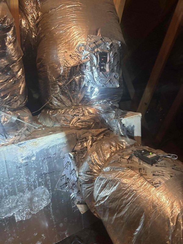 Responded to no cooling complaint for downstairs zone on multi-zone system. Inspected attic-mounted air handler and zone control panel, documenting damaged flexible ductwork with torn outer vapor barrier and exposed insulation. Verified zone damper wiring connections at control board showing proper color-coded wire terminations to multiple thermostats. Identified compromised ductwork as likely cause of reduced airflow and inadequate cooling to downstairs zone.