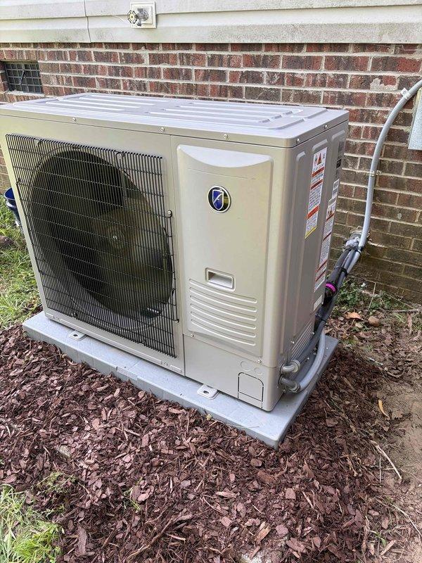 Completed full HVAC system installation including outdoor condenser unit and electric heat furnace. Installed beige condenser unit on concrete pad against exterior brick wall with proper refrigerant line connections and PVC condensate drain routing. Positioned unit in mulched area with adequate clearance for airflow and service access. Interior installation included downflow/upflow electric furnace with all associated hardware and components. Verified all electrical connections, tested system operation, and confirmed proper refrigerant charge levels. Left user's information manual and installation accessories with system for future reference.