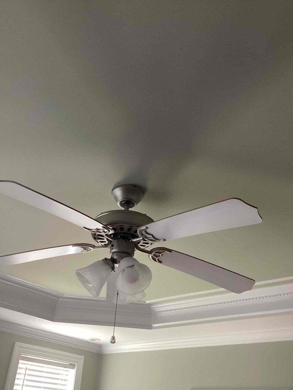Completed follow-up installation of two customer-supplied ceiling fans in downstairs bedrooms after original units arrived damaged. Verified electrical junction boxes were properly rated and secured for fan support, then installed both multi-blade ceiling fans with integrated light kits featuring frosted glass shades and pull-chain controls. Both fans are operational with lighting functioning properly.