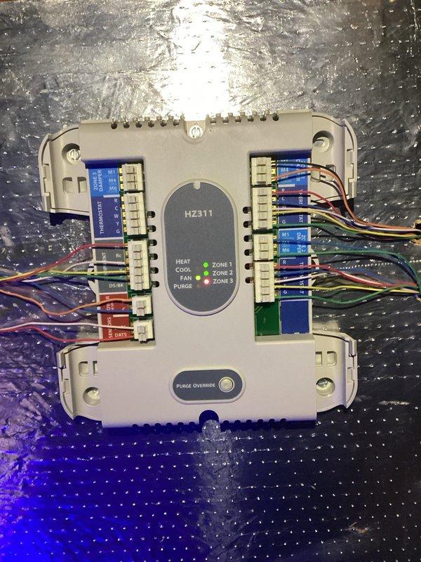 Responded to no airflow complaint on 11-year-old system. Found outdoor unit running but indoor blower not operating. Diagnosed failed run capacitor on blower motor using clamp meter, measuring 47.17 µF on capacitor rated for 45 µF, indicating capacitor degradation. Inspected HZ311 zone control module and verified proper signaling to equipment. Replaced defective run capacitor, restored system operation, and confirmed proper airflow throughout home.