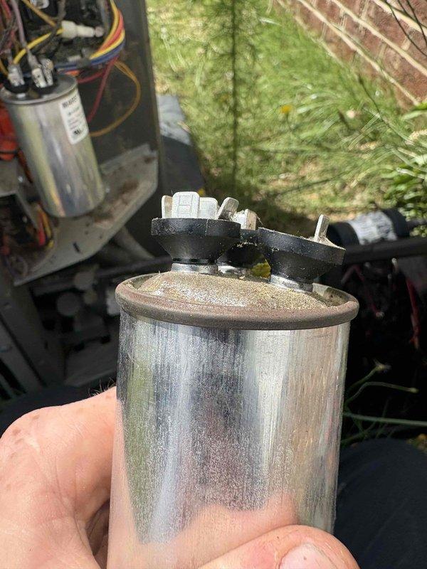 Responded to no-cool call on 2021 system following power outage from storm. Upon arrival, found outdoor unit receiving power but condenser fan motor not operating. Diagnosed failed dual-run capacitor showing visible swelling and discoloration on metallic casing. Removed defective capacitor and installed new replacement capacitor with proper microfarad rating. Verified all electrical connections secure, tested system operation, and confirmed condenser fan motor and compressor now running properly with normal amp draw. System restored to full cooling operation.