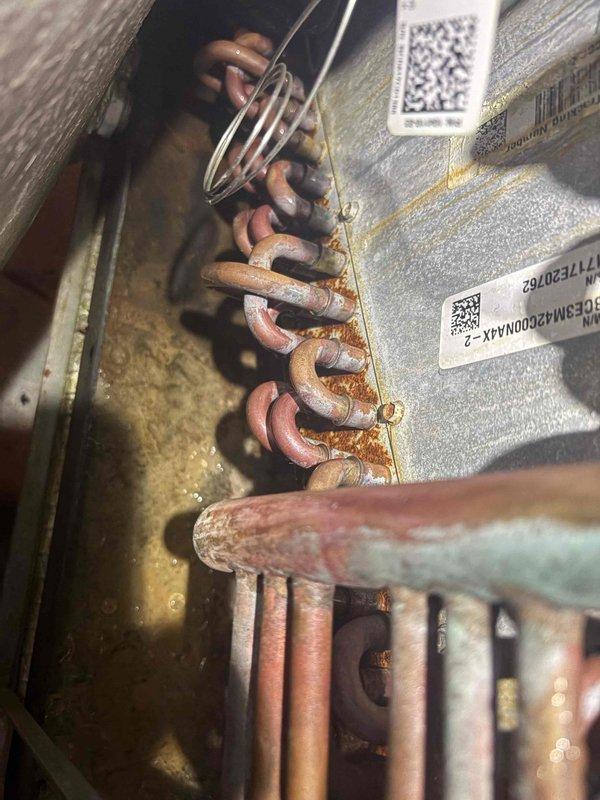 Responded to no cooling complaint on 2019 system with air handler running but no cold air output. Upon inspection, found low amperage draw of 8.4 amps at outdoor unit, indicating compressor failure or refrigerant loss. Visual examination revealed significant oxidation and corrosion on copper refrigerant lines and coil connections, suggesting potential refrigerant leak at evaporator coil assembly. Documented equipment condition with photos and provided customer with repair options for restoring cooling operation.