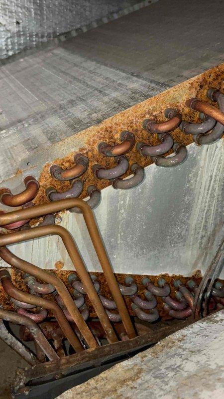 Responded to no cooling call on 11-year-old residential air conditioning system. Upon arrival, inspected indoor evaporator coil assembly located in attic space and found extensive rust and corrosion on refrigerant lines and coil framework, indicating prolonged moisture exposure and system deterioration. Observed compromised refrigerant line integrity with heavy oxidation on copper tubing and mounting brackets. System components showed significant age-related wear consistent with equipment nearing end of service life. Documented conditions with photos showing corroded coil assembly, deteriorated insulation, and moisture damage throughout attic installation area for customer review and replacement recommendations.