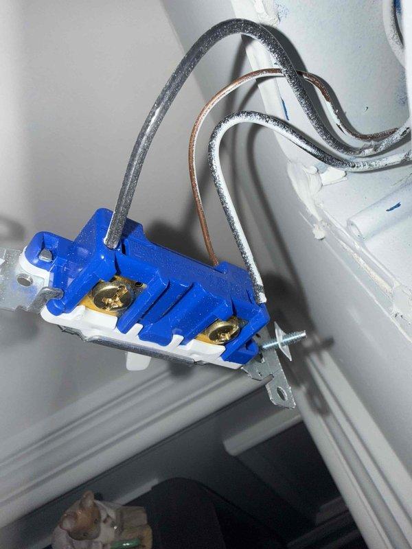 Completed comprehensive 32-point electrical system evaluation on 2020 residential property. Performed electrical panel maintenance including torque verification and connection inspection of all breaker terminals and bus bar connections. Conducted systematic testing of all GFCI outlets and breakers to verify proper ground fault protection and trip functionality. Tested all AFCI breakers to ensure arc fault detection circuits are operating within manufacturer specifications. Performed smoke and carbon monoxide detector maintenance including battery replacement and functional testing of all units. Replaced customer-supplied light bulbs in accessible fixtures up to 12 feet. Cleaned ceiling fans up to 12 feet in height. 

During inspection, identified exposed electrical junction box installation with incomplete wiring termination. Blue plastic outlet box mounted in wall cavity shows proper wire routing with black hot conductors, white neutral conductors, and bare copper ground wires present