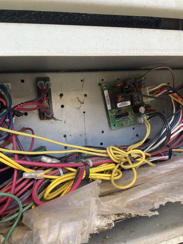 Responded to service call for HVAC system reported to be "acting funky" with cooling still operational. Performed diagnostic inspection of 10-12 year old residential air conditioning unit. Upon examination of control panel and electrical components, discovered excessive dirt, dust, and debris accumulation throughout the system, including cobwebs and deterioration of panel finish. Inspected wiring bundles in attic space, noting significant dust coating on multiple conductors and signs of insulation wear on various colored wires. Documented condition of electrical control board, transformer, terminal connections, and loose coiled wiring in lower panel section. System assessed for potential issues that could lead to complete failure if left unaddressed.