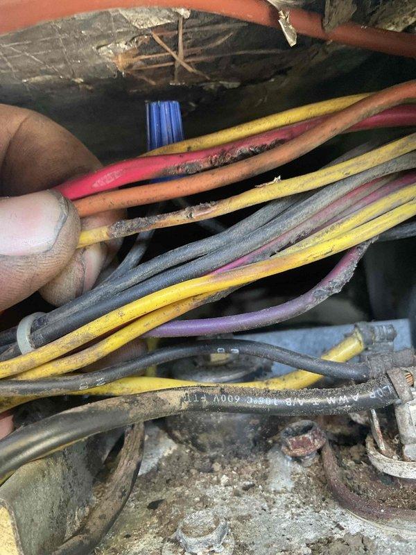 Responded to service call for HVAC system reported to be "acting funky" with cooling still operational. Performed diagnostic inspection of 10-12 year old residential air conditioning unit. Upon examination of control panel and electrical components, discovered excessive dirt, dust, and debris accumulation throughout the system, including cobwebs and deterioration of panel finish. Inspected wiring bundles in attic space, noting significant dust coating on multiple conductors and signs of insulation wear on various colored wires. Documented condition of electrical control board, transformer, terminal connections, and loose coiled wiring in lower panel section. System assessed for potential issues that could lead to complete failure if left unaddressed.