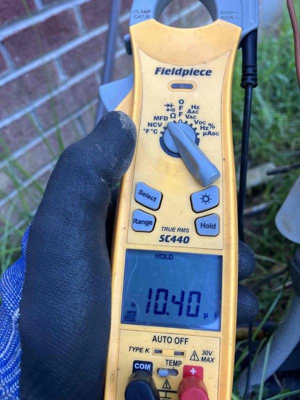 Responded to no cooling complaint on 2009 system where indoor unit was blowing air but not cooling and outdoor fan was not operating. Upon inspection, found evaporator coil heavily loaded with dust and debris restricting airflow. Measured system voltage at 10.4V indicating low voltage issue affecting outdoor unit operation. Documented conditions with multimeter readings and coil condition photos for homeowner review and approval of necessary repairs.