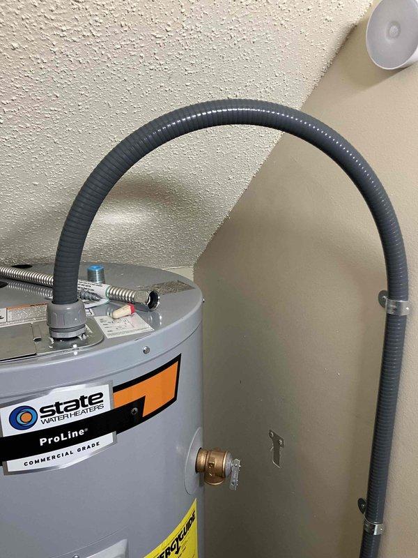Installed dedicated electrical outlet and disconnect for new State ProLine commercial-grade water heater in 1985 residential home. Ran gray flexible conduit vertically along interior wall from new junction box to water heater location, secured with appropriate clips and clamps. Coordinated with plumbing team to ensure same-day completion and restore hot water service to residence.