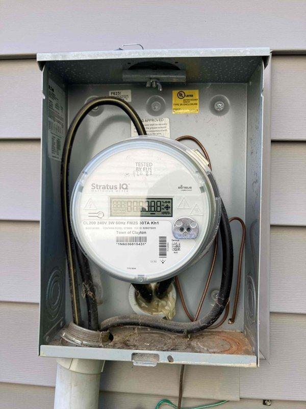 Responded to emergency service call for complete loss of power to major appliances in 2016 construction home. Inspected main electrical meter enclosure and found signs of deteriorated wiring connections at meter base with visible discoloration on conductor terminations, indicating potential overheating or arcing event. Documented Stratus IQ digital meter installation and noted utility company had previously investigated without identifying source of neighborhood-wide power quality issues. Evaluated affected circuit serving kitchen appliances where HVAC system, refrigerator, oven, and stove all failed simultaneously, suggesting power surge or phase loss event. Inspected ceiling-mounted light fixture with intermittent failure history and found loose wire connections at dimmer module requiring attention. Coordinated findings with municipal utility representatives onsite and recommended immediate follow-up for appliance damage assessment and potential utility-side service conductor or tran