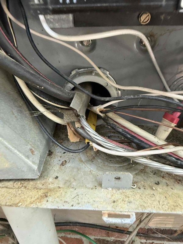 Performed comprehensive electrical inspection for real estate transaction at 1998 residential property. Inspected HVAC electrical connections, including wire terminations, strain relief fittings, and component wiring at mechanical equipment. Documented existing wiring conditions and electrical components serving heating and cooling system, noting wire routing and connection points at equipment terminals.