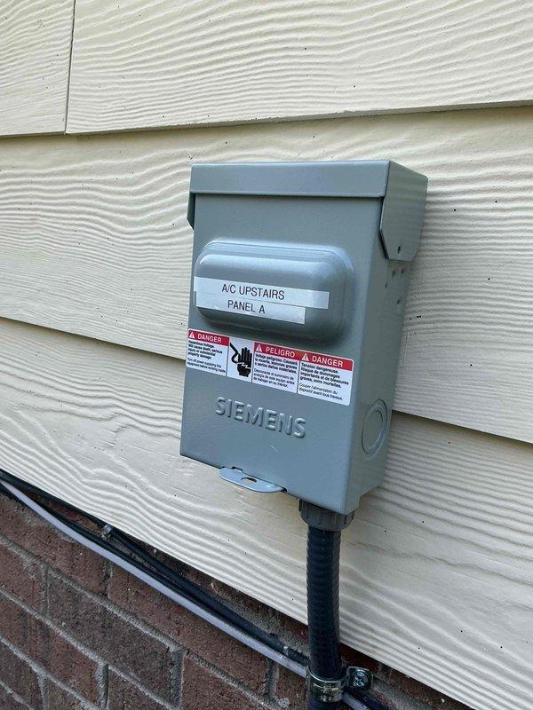 Completed electrical installation for upstairs air conditioning system. Installed dedicated 240V disconnect switch on exterior wall with proper labeling and conduit routing, and connected circuit breakers in main electrical panel with clear circuit identification for the new HVAC unit.