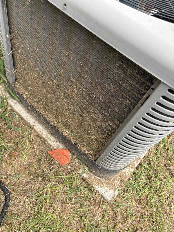 Responded to service call for downstairs system entering standby mode prematurely and inadequate cooling, with indoor temperature reaching 80 degrees after only 5 hours of runtime. Upon inspection of the 10-year-old outdoor condenser unit, found extensive accumulation of dirt, grass clippings, organic debris, and matted fibrous material heavily restricting airflow through the condenser coils and heat exchanger fins. The buildup was significantly impacting system efficiency and causing the unit to overheat and shut down prematurely. Documented the condition of the dirty coils with photographs showing the severity of contamination on both exterior surfaces and between the aluminum fins, which would require thorough cleaning to restore proper system operation and prevent continued thermal shutdowns.
