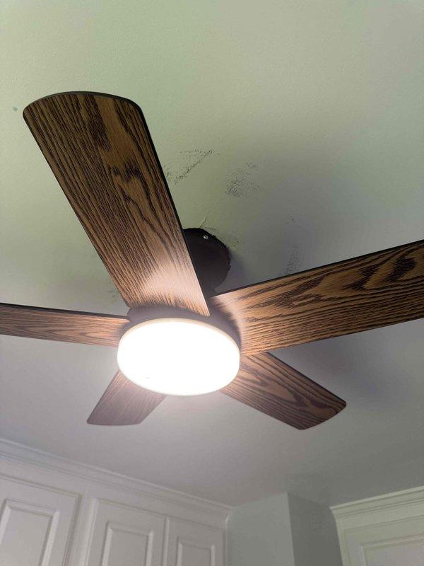 Completed ceiling fan upgrades in two separate rooms of the residence. Removed existing ceiling fan fixtures and installed new replacement units, including a five-blade model with wood-grain finish and oil-rubbed bronze housing with integrated light kit, and a four-blade contemporary model with dark wood-grain blades and cylindrical LED light fixture. Verified proper electrical connections, tested fan operation at all speeds, and confirmed light fixture functionality on both installations.