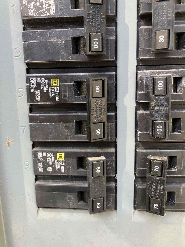 Inspected existing electrical panel in preparation for installation of new 90-amp breaker to feed sub-panel in crawl space. Work is pending arrival of the specified breaker, which may not have been ordered yet. Documented current panel configuration showing Square D load center with multiple circuit breakers ranging from 50 to 100 amps installed.
