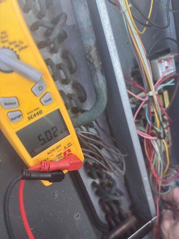Responded to no cooling call where system was not turning on. Upon arrival, performed diagnostic testing using multimeter and measured 5.02 volts at electrical components. Inspected evaporator coil and found significant dirt and debris accumulation on fin surfaces, particularly on one side, which was restricting airflow and system performance. Documented equipment condition with photos showing contaminated coil requiring cleaning and electrical measurements for further troubleshooting of power supply issues preventing unit operation.