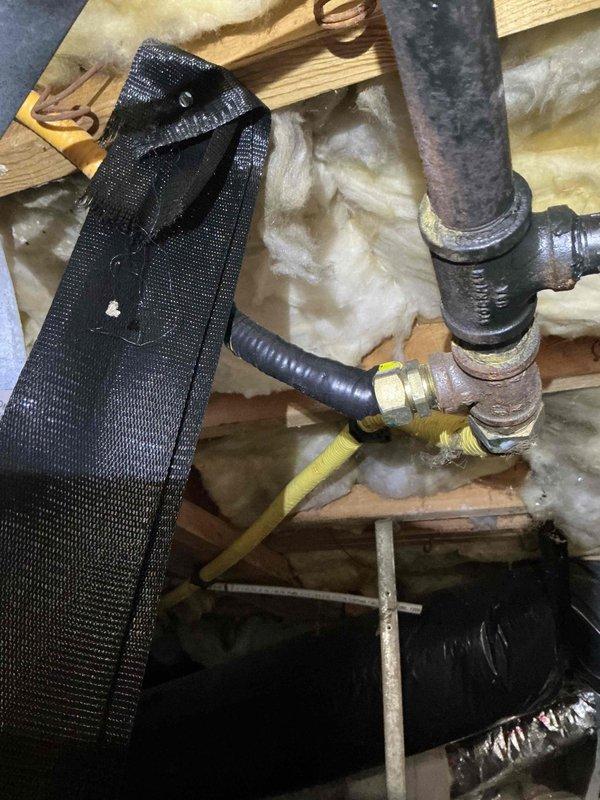 # HVAC System Installation Recall - Permit Compliance Issue

Responded to failed permit inspection on recently installed 90% AFUE Lennox gas split system. Upon arrival, identified code violation involving CSST (Corrugated Stainless Steel Tubing) gas line jacketing secured with standard electrical tape rather than approved dielectric tape as required by electrical code. CO alarms were observed installed within the residence. Documented installation deficiencies with photographic evidence showing gas line connections, PVC venting configuration, and CSST routing through structural framing with improper tape application. System requires correction of CSST jacketing method to meet electrical bonding requirements before final permit approval can be obtained.