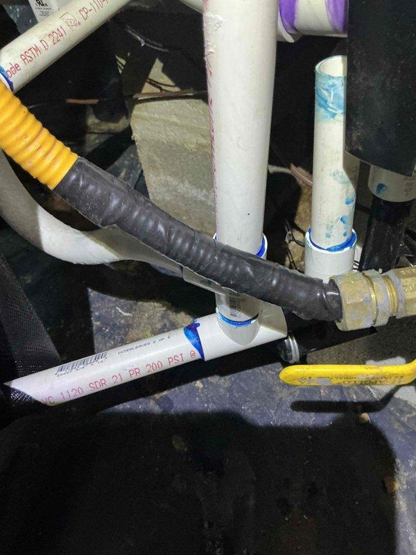 # HVAC System Installation Recall - Permit Compliance Issue

Responded to failed permit inspection on recently installed 90% AFUE Lennox gas split system. Upon arrival, identified code violation involving CSST (Corrugated Stainless Steel Tubing) gas line jacketing secured with standard electrical tape rather than approved dielectric tape as required by electrical code. CO alarms were observed installed within the residence. Documented installation deficiencies with photographic evidence showing gas line connections, PVC venting configuration, and CSST routing through structural framing with improper tape application. System requires correction of CSST jacketing method to meet electrical bonding requirements before final permit approval can be obtained.