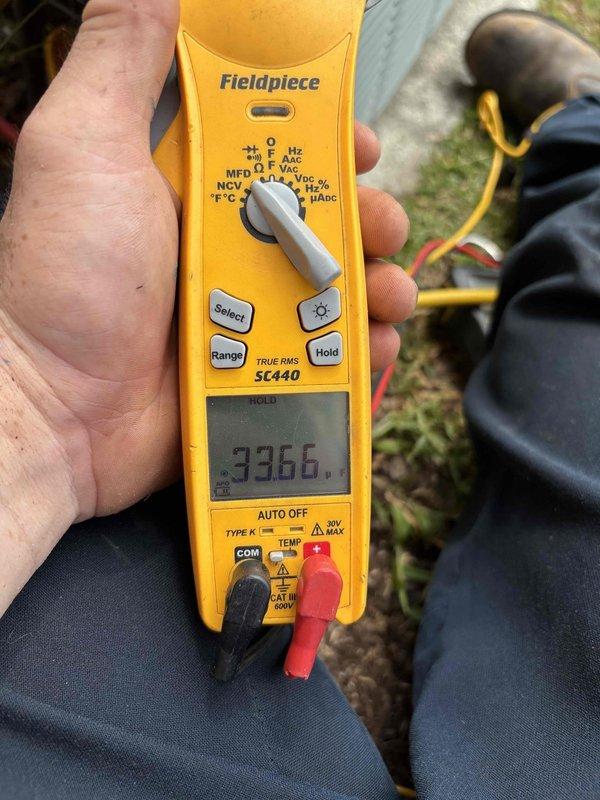 Responded to no cooling complaint on upstairs air conditioning system in a two-system residence with 10-year-old equipment. Accessed attic-mounted air handler and performed diagnostic testing of electrical components using digital multimeter, which revealed capacitor reading of 3366 on testing meter. Identified failed capacitor as root cause of cooling failure and completed necessary repairs to restore proper system operation.