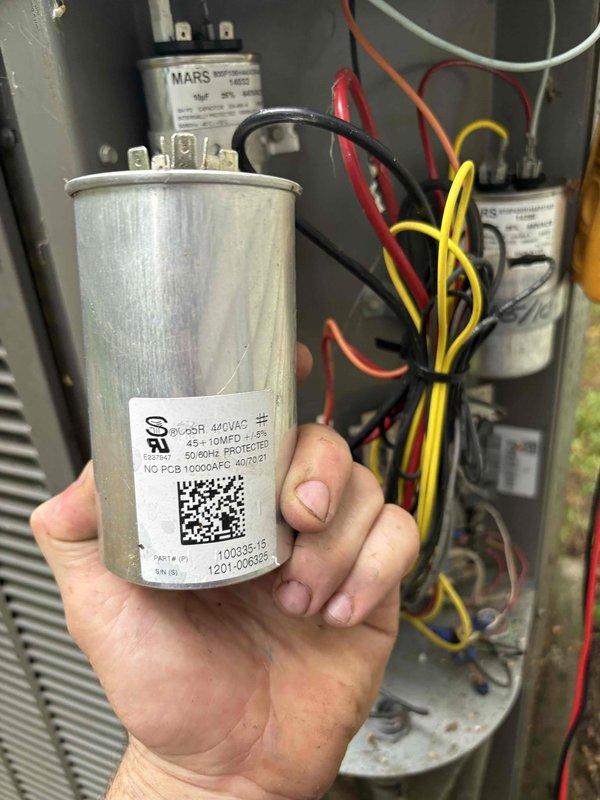 Replaced defective dual capacitor rated at 440VAC 45+10 MFD in outdoor HVAC unit. Verified proper amperage draw of 12.6A after installation and confirmed system operation with all electrical connections secure.