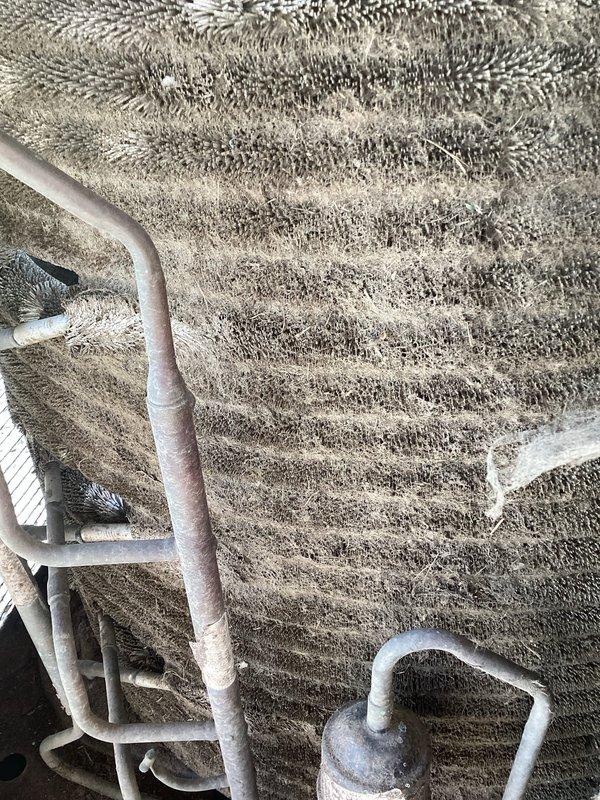 Responded to no cooling complaint on 10-15 year old central air system. Found customer had bypassed pressure switch due to suspected voltage loss across switch. Upon inspection, discovered evaporator coil completely frozen with heavy ice buildup throughout interior cabinet. Measured compressor amperage at 1.0A using clamp meter, confirming system operation. Diagnosed frozen coil condition caused by restricted airflow or low refrigerant charge, which resulted in pressure switch opening as safety mechanism to prevent compressor damage. Advised customer that bypass of pressure switch is unsafe and must be removed, as switch protects system from operating under unsafe conditions that caused freezing issue.