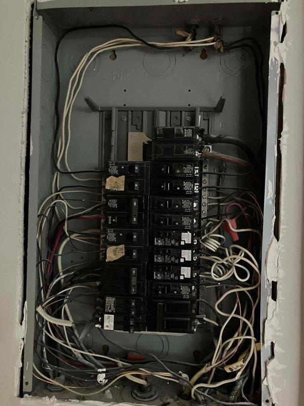 Responded to report of non-functioning dryer outlet and two bathroom outlets in 1959 home where homeowner reported crackling sound from breaker. Upon inspection, found electrical panel exhibiting severe deterioration with heavy rust on metal frame, corroded bus bars with oxidation buildup, and compromised breaker connections throughout. Panel showed signs of prolonged moisture exposure and age-related degradation, creating unsafe operating conditions. Documented extensive corrosion on breakers, mounting hardware, and neutral/ground bars, along with disorganized wiring and accumulated contamination within enclosure that posed fire and shock hazards requiring immediate panel replacement to restore safe electrical service to affected circuits.