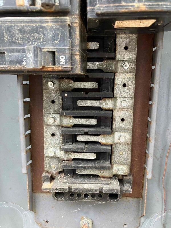 Responded to report of non-functioning dryer outlet and two bathroom outlets in 1959 home where homeowner reported crackling sound from breaker. Upon inspection, found electrical panel exhibiting severe deterioration with heavy rust on metal frame, corroded bus bars with oxidation buildup, and compromised breaker connections throughout. Panel showed signs of prolonged moisture exposure and age-related degradation, creating unsafe operating conditions. Documented extensive corrosion on breakers, mounting hardware, and neutral/ground bars, along with disorganized wiring and accumulated contamination within enclosure that posed fire and shock hazards requiring immediate panel replacement to restore safe electrical service to affected circuits.