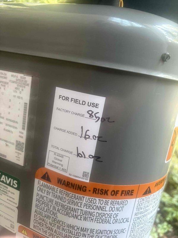 Responded to no cooling complaint on central air system less than 5 years old with previous control board replacement. Upon inspection, identified refrigerant charge discrepancy on outdoor unit containing R-454B refrigerant. Verified system had received 16 oz field charge added to 85 oz factory charge for total of 61 oz, indicating potential calculation error or leak. Evaluated indoor airflow and thermostat operation to rule out inconsistent cooling patterns reported by occupant.