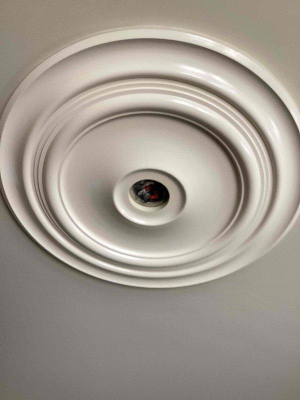 Installed customer-supplied chandelier with black metal frame and multiple glass shades in residential foyer with 10-foot ceiling. Mounted decorative white ceiling medallion with concentric circular pattern to ceiling junction box, secured chandelier chain and canopy, made electrical connections, and tested all lamp sockets for proper operation.