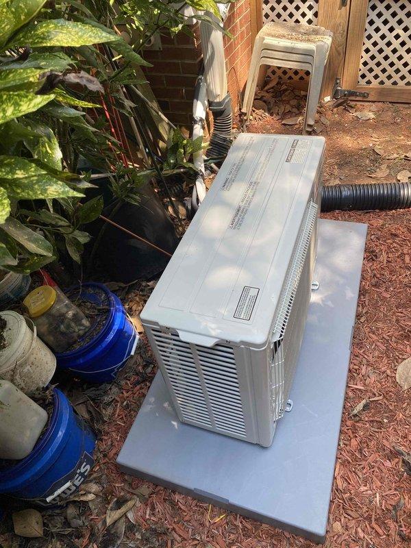 Completed installation of ductless mini-split air conditioning system at residential property. Outdoor condenser unit was mounted on concrete pad in side yard area adjacent to brick exterior wall, with electrical disconnect box installed and condensate drain line properly routed. Interior air handler component was installed in garage space with appropriate electrical connections made to existing panel.