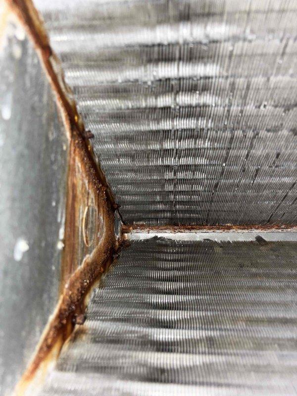 Responded to possible recall for system cycling irregularly with high and low operation sounds. Upon inspection, discovered extensive rust and corrosion on evaporator coil copper piping, connection joints, and mounting frame components indicating significant moisture exposure and deterioration. Documented corroded areas with photographs showing oxidation on refrigerant lines, deteriorated paint on metal housing, and rust bleeding at panel seams. Determined cycling issue unrelated to previous service work performed.