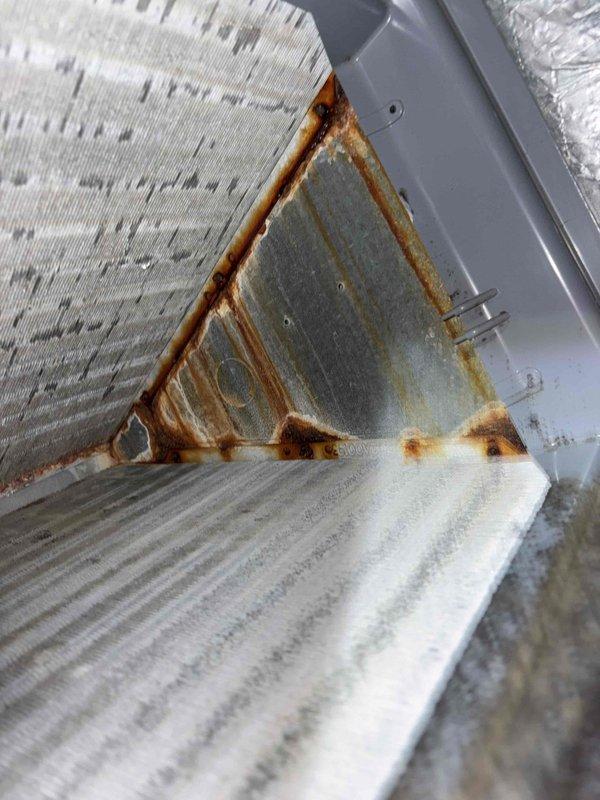 Responded to possible recall for system cycling irregularly with high and low operation sounds. Upon inspection, discovered extensive rust and corrosion on evaporator coil copper piping, connection joints, and mounting frame components indicating significant moisture exposure and deterioration. Documented corroded areas with photographs showing oxidation on refrigerant lines, deteriorated paint on metal housing, and rust bleeding at panel seams. Determined cycling issue unrelated to previous service work performed.