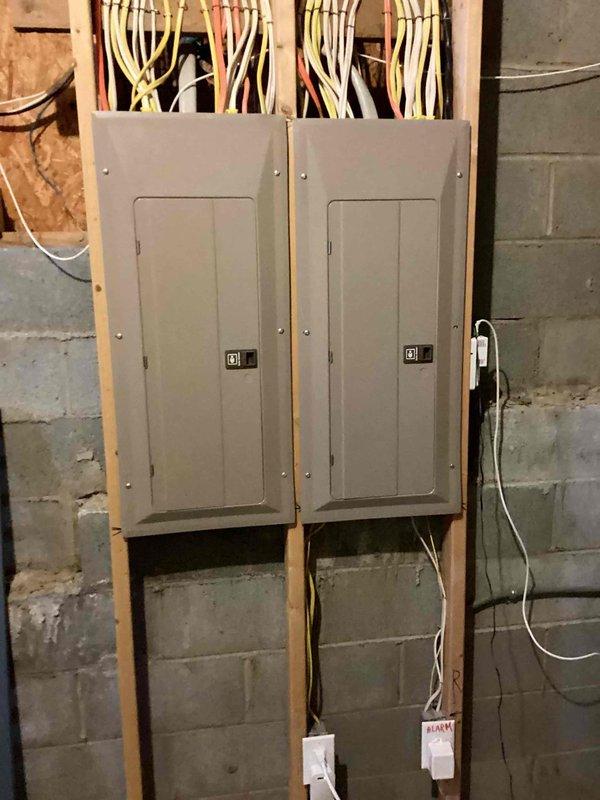 Responded to service call regarding interconnected smoke detectors experiencing frequent false alarms originating from second-floor units in a 2005-built residence with 15 total detectors. Inspected electrical panels and smoke detector circuits to diagnose the cause of weekly nuisance alarms that were triggering the entire interconnected system throughout the home. Documented panel configuration and circuit layout for the smoke detection system.