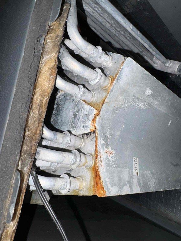 Responded to no-cooling call on heat pump system over ten years old. Upon arrival, confirmed outdoor unit fan motor operating but compressor not engaging. Diagnosed failed dual run capacitor preventing compressor operation. Replaced defective capacitor with proper rated replacement, restored full system operation, and verified proper amperage draw on compressor and condenser fan motor. During inspection, documented significant rust corrosion on indoor air handler refrigerant line connections and cabinet panels indicating historical moisture intrusion, as well as aging ductwork insulation in attic space showing deterioration and separation at seams. System now cooling properly with all components functioning within normal operating parameters.