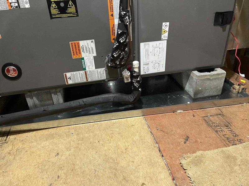 Completed full system replacement installation to address inadequate cooling performance with interior temperature reaching 78°F. Installed Rheem RD18AY48AJVCA 4-ton variable-speed heat pump condenser (18 SEER2, R-454B refrigerant) and Rheem RH2VY6024STACNJ 5-ton multi-position air handler with 2-stage operation. Added Tutco 10kW auxiliary heat kit for supplemental heating capacity. Installed two Honeywell TH2320WF4010/U smart thermostats for dual-zone control. Added emergency drain pan with float switch protection to prevent water damage. Performed complete system startup, refrigerant charge verification, and airflow testing. Documentation photos revealed significant frost accumulation on existing ductwork in attic space, indicating severe condensation issues and temperature differential problems that contributed to system inefficiency. Standing water observed in condensate management area of air handler installation. All debris removed, old equipment disposed of properly, and work ar