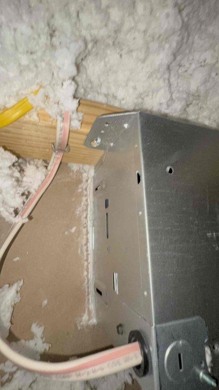 Responded to complaint of recurring mildew stains around master bathroom exhaust fan. Inspected attic space above bathroom and found improper exhaust fan termination with inadequate venting causing moisture accumulation in ceiling cavity. Documented damaged insulation and drywall deterioration around exhaust ductwork, along with improperly secured electrical junction box and wiring connections that required attention for code compliance and safety.