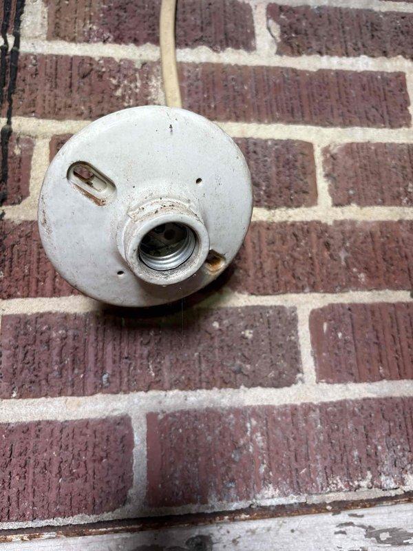Responded to vacant property for two malfunctioning cellar lights. Upon inspection, discovered severely damaged electrical component with evidence of arcing, melting, and burn damage to switch or outlet box mounted on wooden framing—immediate safety hazard requiring replacement. Second issue involved porcelain pull-chain light fixture that would not shut off due to faulty internal socket mechanism. Documented both conditions with photographs and contacted property owner with findings and repair recommendations to address electrical hazards prior to property sale.