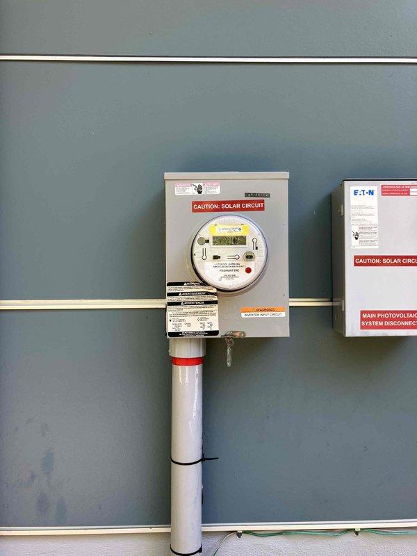 Responded to service call for flickering lights, non-functioning ceiling fan, and sparking switches in a 2018 home with solar photovoltaic system. Performed comprehensive inspection of main electrical panel and solar disconnect system, identifying potential loose connections or shared neutral issues affecting lighting circuits. Documented electrical panel configuration showing properly organized circuit breakers, grounding bus bars, and solar integration components including main photovoltaic system disconnect and metered service entrance, with all wiring appearing code-compliant and well-maintained.