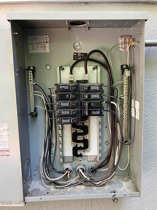 Responded to service call for flickering lights, non-functioning ceiling fan, and sparking switches in a 2018 home with solar photovoltaic system. Performed comprehensive inspection of main electrical panel and solar disconnect system, identifying potential loose connections or shared neutral issues affecting lighting circuits. Documented electrical panel configuration showing properly organized circuit breakers, grounding bus bars, and solar integration components including main photovoltaic system disconnect and metered service entrance, with all wiring appearing code-compliant and well-maintained.
