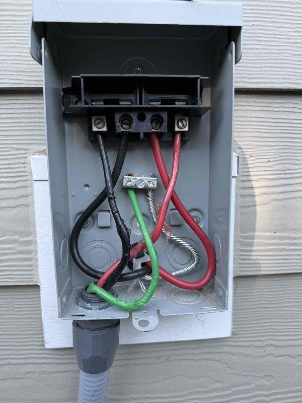 Completed annual 32-point electrical system evaluation on 2019 residential property. Performed electrical panel maintenance including torque verification and connection inspection of all terminations. Tested all GFCI outlets and breakers for proper shock protection functionality and confirmed arc fault breakers were operating within specifications for fire protection. Conducted smoke and carbon monoxide detector maintenance including battery replacement and operational testing of all units. Inspected exterior disconnect box and verified proper wire terminations on terminal block with black, red, and green conductors properly secured. Identified damaged drywall surrounding interior outlet requiring repair, with outlet itself functioning properly despite compromised wall material around electrical box opening. Replaced customer-supplied light bulbs in fixtures up to 12 feet and performed ceiling fan cleaning service. All electrical components tested and verified operational per manufactu