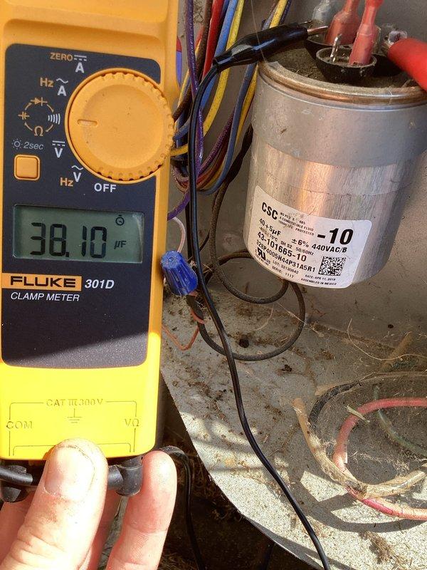 Responded to no cooling complaint on 3-year-old residential HVAC system. Upon inspection, found outdoor condenser coil heavily contaminated with dirt, dust, grass clippings, and organic debris significantly restricting airflow. Tested run capacitor and found it reading 38.10 μF against rated capacity of 10 μF, indicating capacitor failure. Cleaned condenser coil to restore proper airflow and replaced failed run capacitor with proper rated component. Verified system operation with thermostat communication restored and unit cooling properly.