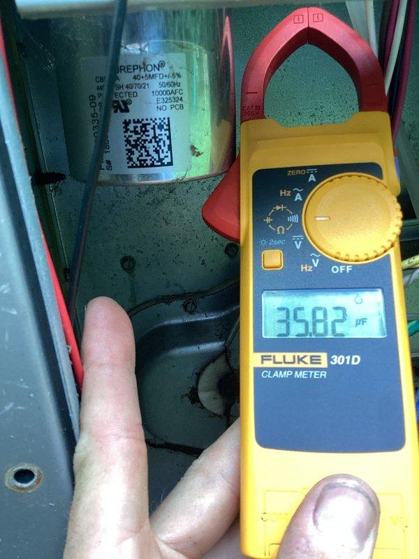 Responded to no cooling complaint on residential air conditioning system. Upon arrival, performed visual inspection of outdoor condensing unit and found condenser coil heavily obstructed with dirt, dust, and debris accumulation, particularly in lower two-thirds of coil surface. Excessive buildup was restricting airflow through coil fins, significantly impeding heat transfer capability and preventing unit from operating efficiently.

Accessed electrical compartment and performed diagnostic testing of system components. Used clamp meter to measure capacitance of run capacitor, obtaining reading of 35.82 μF. Verified capacitor specifications against manufacturer nameplate on REPHON brand capacitor. Inspected refrigerant line connections and electrical wiring for signs of damage or deterioration.

Primary issue identified as severely restricted condenser coil preventing adequate heat rejection from refrigerant system, resulting in loss of cooling capacity. Recommended thorough coil cleanin