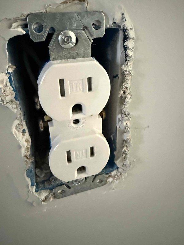 Completed annual 32-point electrical system evaluation on 2018 home. Performed electrical panel maintenance including torque verification and connection inspection. Tested all GFCI outlets and breakers for proper shock protection functionality. Verified arc fault breakers for fire protection performance. Conducted smoke and CO2 detector maintenance with battery replacement and operational testing. Replaced customer-supplied light bulbs in fixtures up to 12 feet and cleaned ceiling fans up to 12 feet. Noted wall damage around one duplex receptacle requiring drywall repair. All electrical components tested within normal operating parameters.