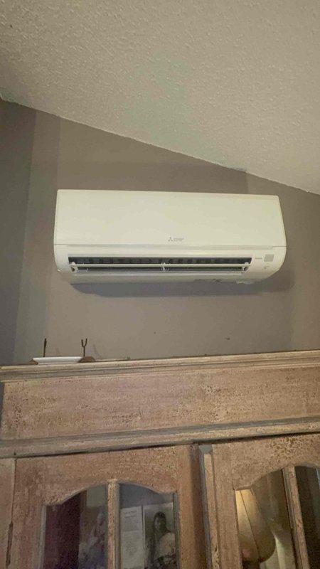 Responded to no cool call on Mitsubishi Electric mini-split system in living room with water draining indoors instead of outdoors. Diagnosed clogged condensate drain line preventing proper drainage. Cleared obstruction from drain line, verified proper water flow to exterior, tested system operation with manifold gauges, and confirmed unit cooling properly with no further drainage issues.