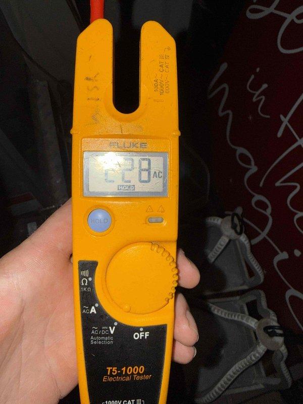 Responded to report of insufficient power to AC disconnect box as identified by HVAC technician. Upon investigation, discovered severely fire-damaged electrical junction box with completely charred wiring and melted insulation indicating previous electrical fire or extreme heat event. Measured voltage at 228V AC using Fluke T5-1000 electrical tester. Junction box mounted to wooden framing showed extensive internal carbonization and heat distortion of metal components, rendering the electrical connection unsafe and non-functional. Documented hazardous condition and recommended immediate replacement of damaged junction box, all affected wiring, and thorough inspection of circuit to ensure safe restoration of proper power supply to AC disconnect.