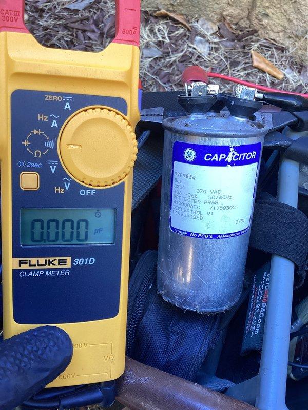 Responded to no cooling call at commercial building with 11+ year old system. Upon arrival, confirmed outdoor condensing unit was not operating. Tested capacitor using Fluke 301D clamp meter and found failed run capacitor preventing compressor from starting. Replaced defective GE 370VAC capacitor with new unit, restored power, and verified system operation with proper compressor startup and cooling cycle.