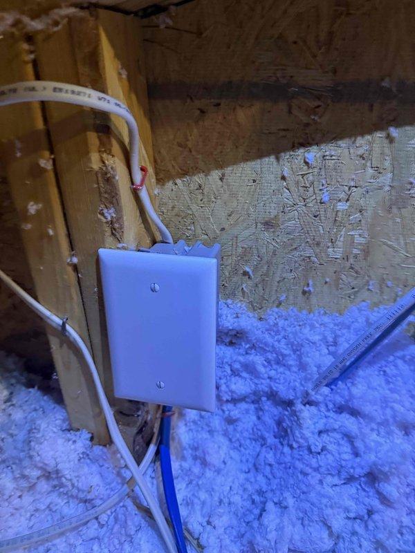 Installed a new weatherproof electrical outlet in the sauna by tapping into the existing lighting circuit. Ran Romex cable through the attic space, secured wiring at junction box, and mounted a gray flip-up style outlet cover on the wooden wall. Customer was advised that adding this outlet to the lighting circuit may cause the breaker to trip under heavy load conditions.